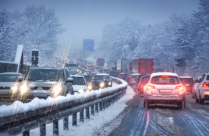 tail lights and headlights of lanes of traffic stuck in poor road conditions