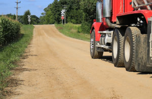 photo of a truck driving down an unpaved road toward a stop sign