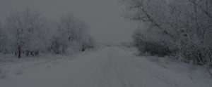 photo of a road covered in ice and snow in a rural area