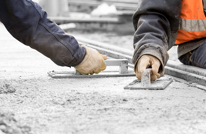 Photo of two people using tools to smooth fresh cement