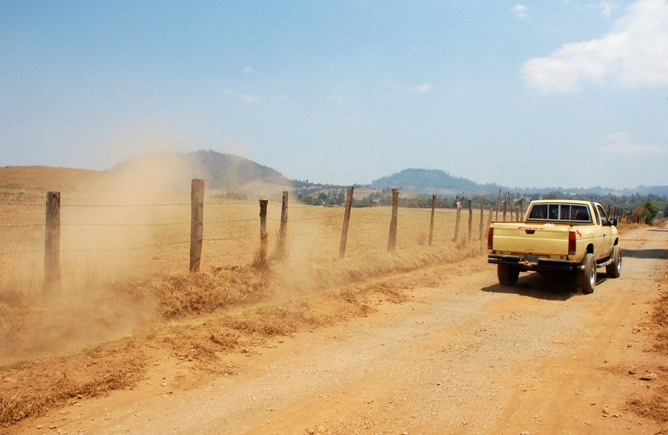 Photo of a very dusty rural road with a truck driving