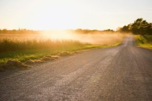 Dust control is an important part of Indiana Gravel Road Maintenance image shows gravel road at sunrise