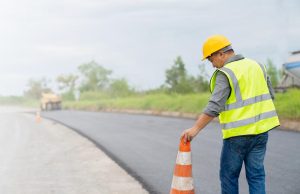 Enhance the stability of reclaimed roads in your next Indiana Road Reclamation project with help from Great Lakes Chloride image shows worker setting cone