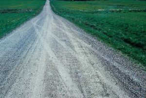 Tackle Ohio Gravel Road Erosion Control with help from Great Lakes Chloride image shows gravel road through green field
